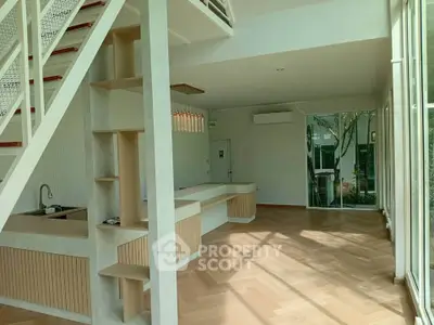 Spacious modern living room with open layout and large windows, featuring stylish wooden flooring and staircase.