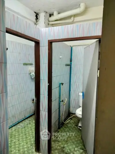 Compact bathroom with tiled walls and floor, featuring a toilet and shower area.