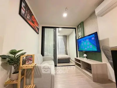Modern living room with sleek design, featuring a cozy sofa, wall-mounted TV, and sliding glass doors to bedroom.