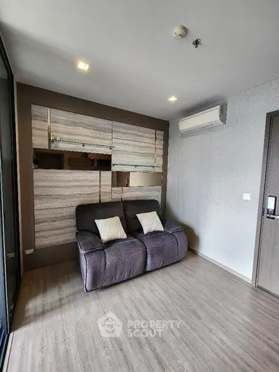 Modern living room with sleek design and air conditioning, featuring a cozy sofa and stylish wooden flooring.