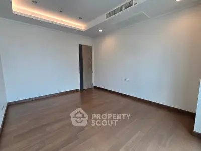 Spacious empty room with wooden flooring and modern ceiling design, perfect for customization.