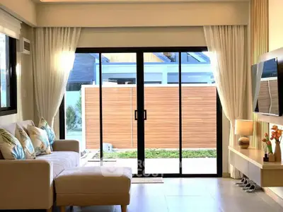 Modern living room with sliding glass doors opening to a private garden, featuring elegant decor and natural light.