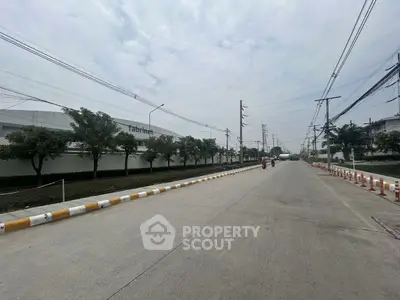 Expansive industrial road view with surrounding greenery and clear sky.