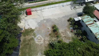 Spacious outdoor area with potential for development, featuring greenery and a storage unit.