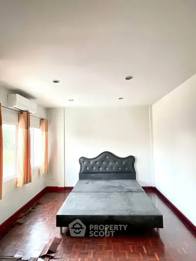 Spacious bedroom with elegant bed frame and natural light from large windows.