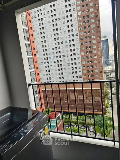 High-rise apartment view with balcony and washing machine overlooking cityscape.