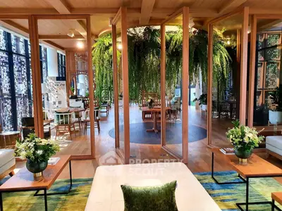 Luxurious living room with open layout and lush greenery, featuring elegant wooden accents and modern decor.