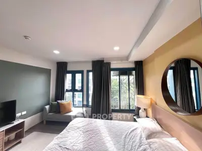 Modern bedroom with stylish decor and large windows offering natural light.
