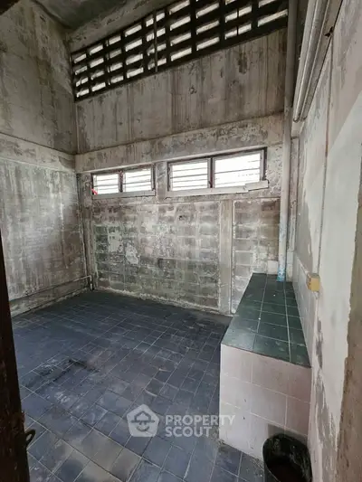 Spacious industrial-style room with high ceilings and tiled flooring, perfect for creative renovation.