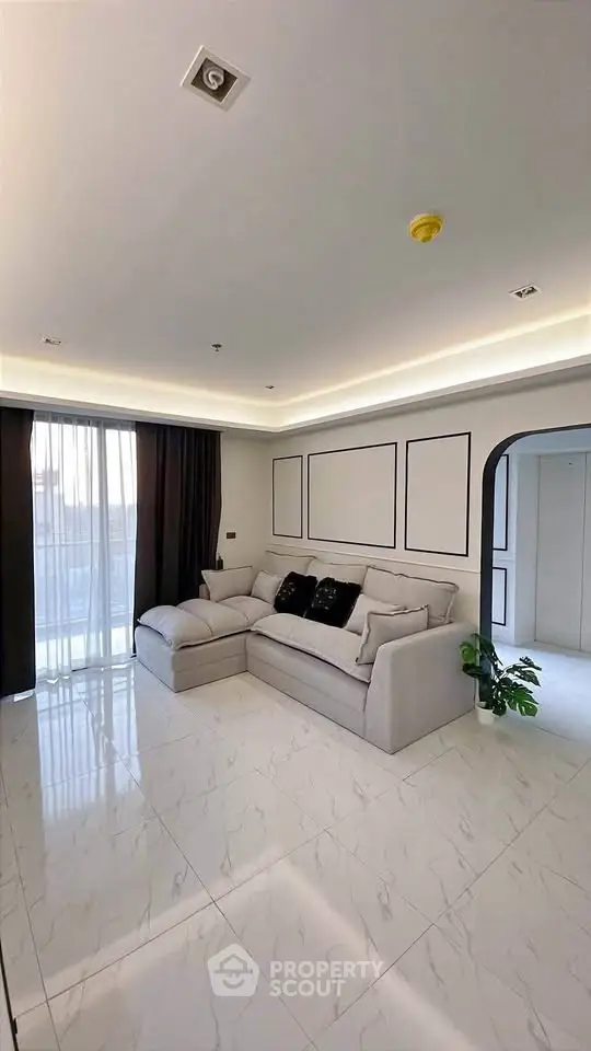 Elegant living room with modern decor and natural light, featuring a cozy sectional sofa and stylish wall accents.