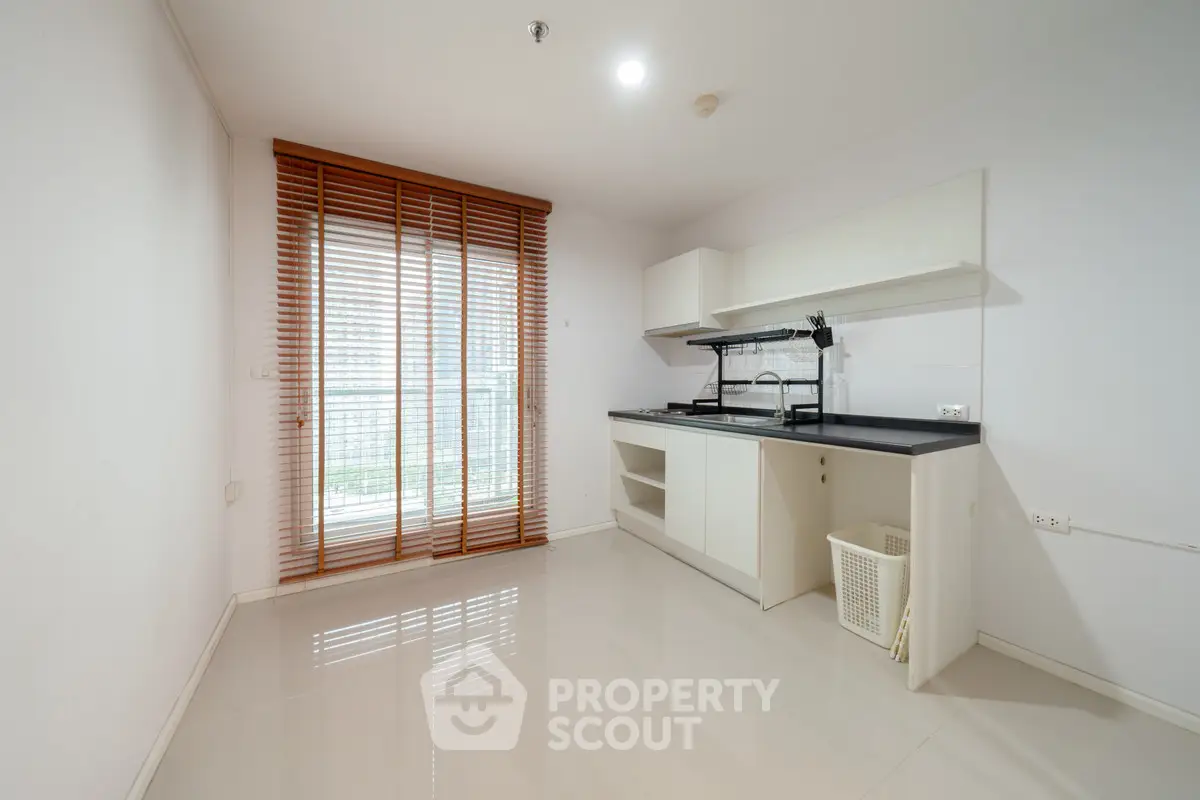 Modern minimalist kitchen with sleek cabinetry and large window for natural light.