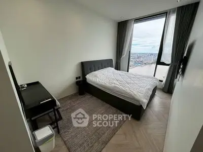 Modern bedroom with city view, featuring a cozy bed and sleek furnishings.