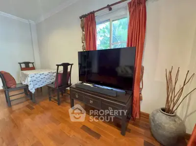 Charming living room with elegant wooden furniture and large TV, perfect for cozy family gatherings.