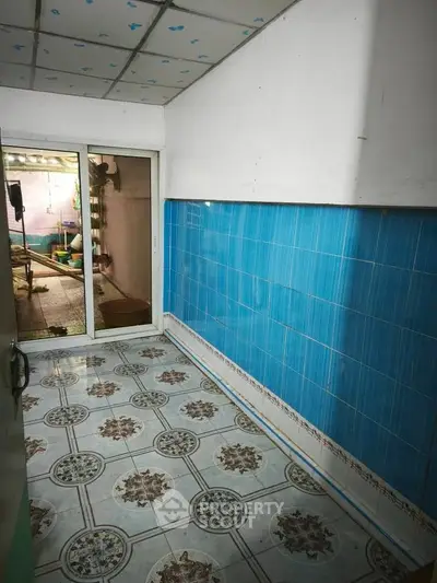 Charming kitchen space with vibrant blue tiles and patterned flooring, opening to a cozy outdoor area.