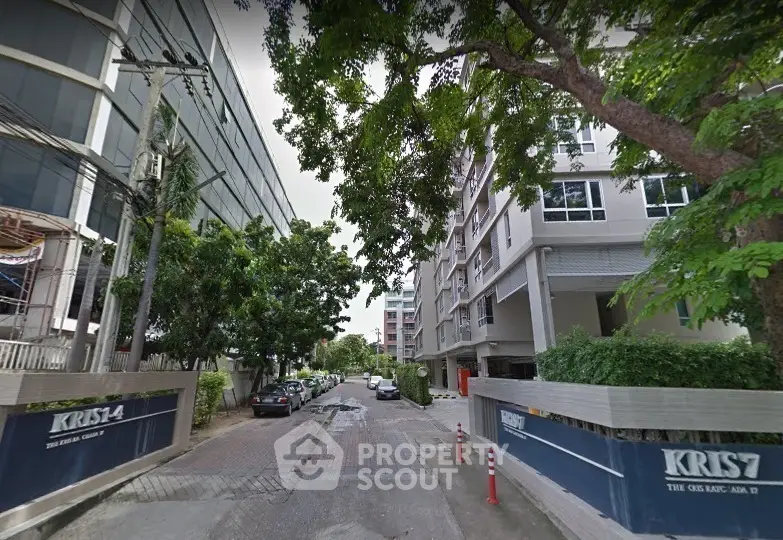 Modern urban apartment building with lush greenery and street view