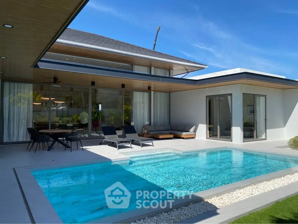 Luxurious modern villa with private pool and spacious outdoor seating area under clear blue skies.