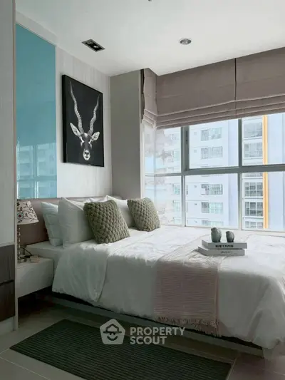 Modern bedroom with large windows and stylish decor in urban apartment.
