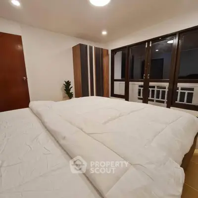 Cozy bedroom with large bed and modern wardrobe, featuring warm lighting and balcony access.