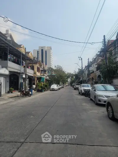Charming urban street view with parked cars and residential buildings, ideal for city living enthusiasts.