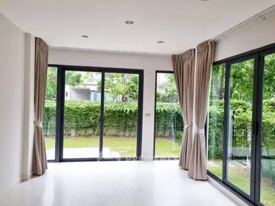 Spacious living room with large glass doors opening to a lush garden view, perfect for natural light lovers.