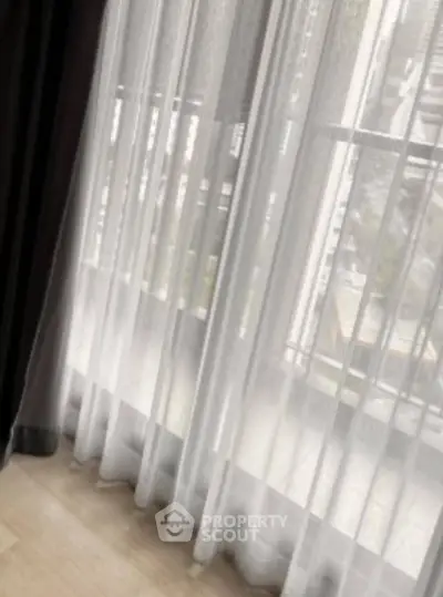 Elegant floor-to-ceiling window with sheer curtains offering a serene city view.