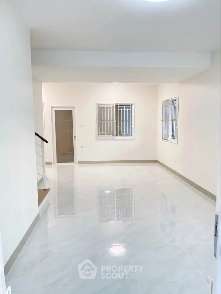Spacious and bright living room with glossy tiled floors and large windows.