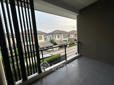 Spacious balcony with modern railing offering a serene neighborhood view, perfect for relaxation.