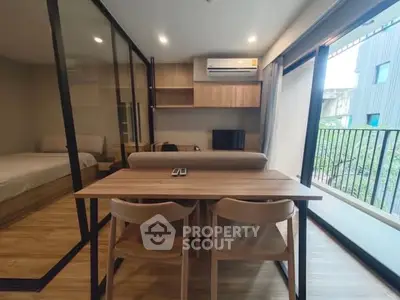 Modern apartment interior with open layout, featuring a cozy living area and balcony view.