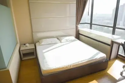 Spacious bedroom with large windows offering stunning city views, perfect for urban living.