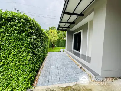 Charming modern home exterior with lush green garden and sleek pathway.