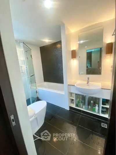 Modern bathroom with sleek design, featuring a bathtub and glass shower enclosure.