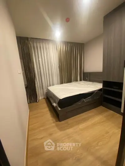 Modern bedroom with sleek wooden flooring and stylish curtains in a contemporary apartment.