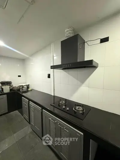Modern kitchen with sleek black countertops and gas stove, featuring ample cabinet space and minimalist design.