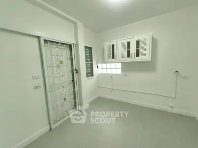 Spacious utility room with white cabinets and tiled floor, perfect for laundry or storage.