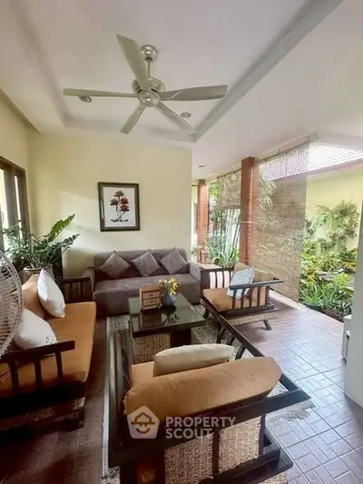 Charming indoor-outdoor living space with cozy seating and lush garden view, perfect for relaxation.