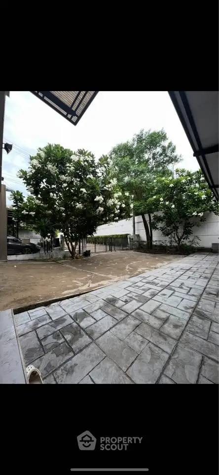 Spacious outdoor area with paved patio and lush greenery, perfect for relaxation and gatherings.