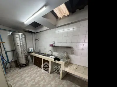 Spacious kitchen with industrial water tank and tiled countertops, ideal for culinary enthusiasts.