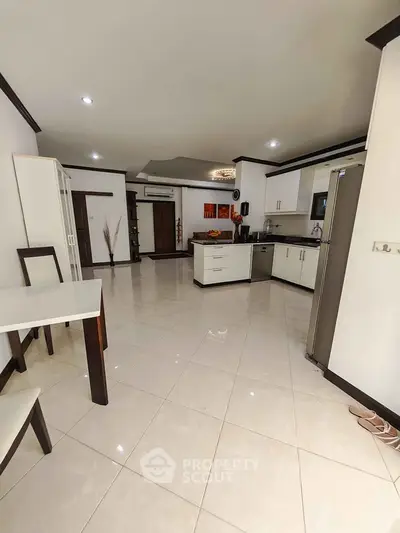 Spacious modern kitchen with sleek design and open layout, featuring stainless steel appliances and elegant tile flooring.