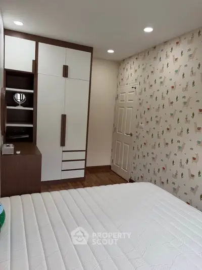 Charming bedroom with modern wardrobe and playful wallpaper, perfect for a cozy and stylish living space.