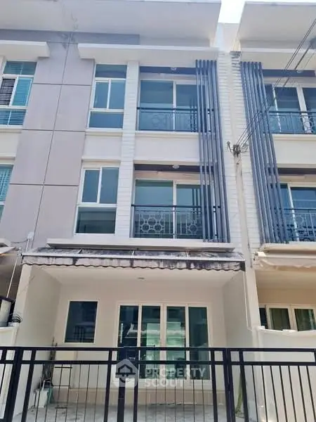 Modern townhouse exterior with balcony and gated entrance