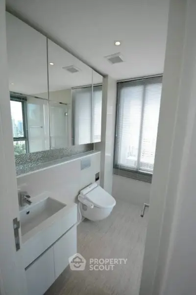Modern bathroom with sleek fixtures and city view, featuring a stylish toilet and vanity.