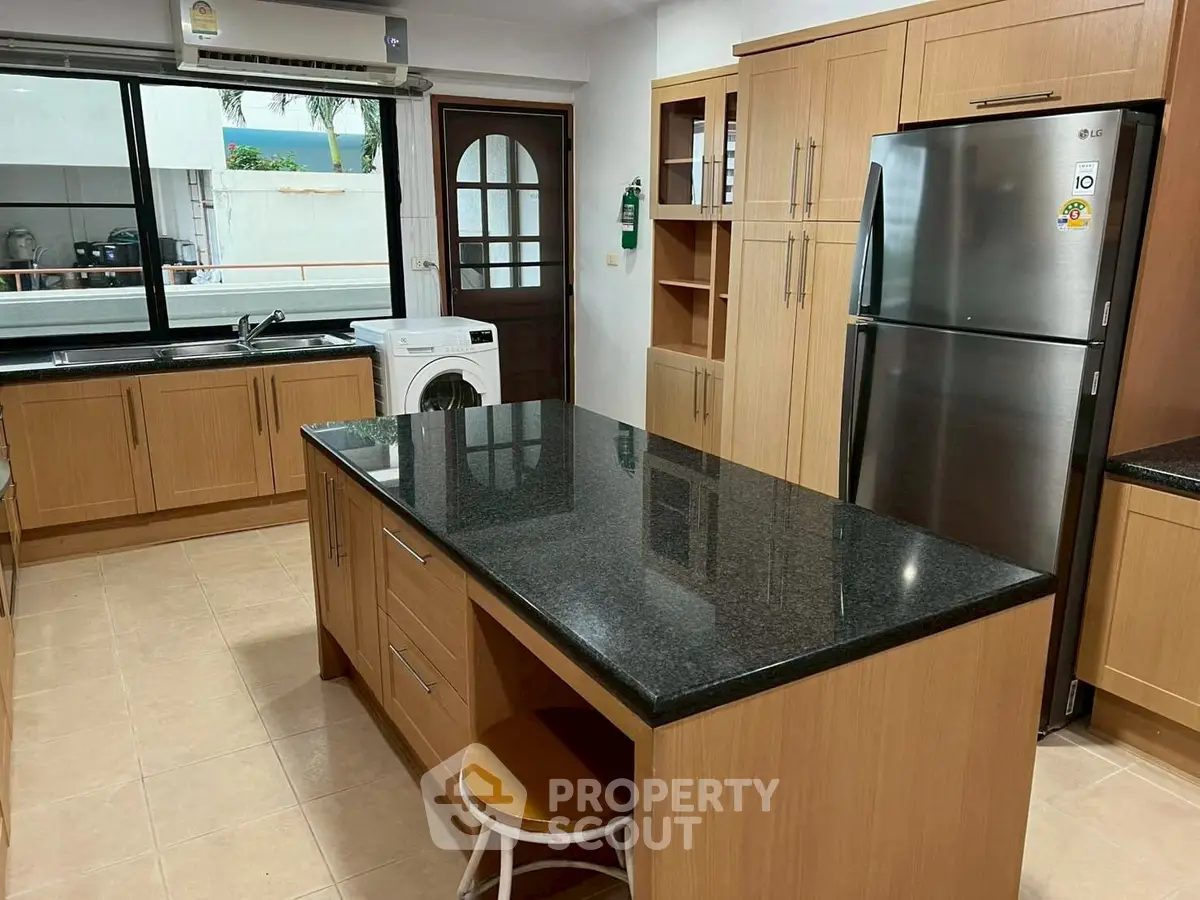 Spacious kitchen with modern appliances and island counter in elegant wooden finish.