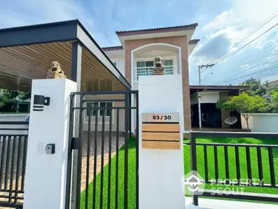 Modern two-story house with gated entrance and lush green lawn