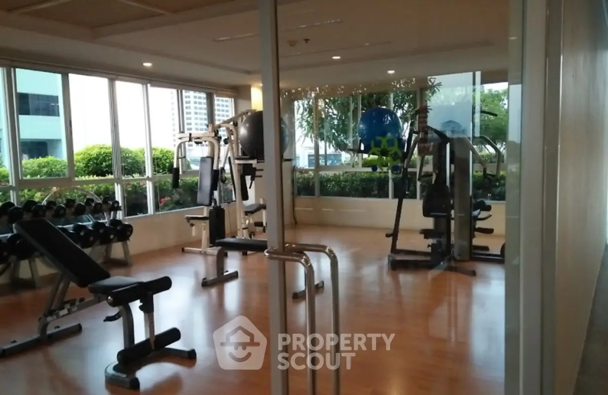 Spacious gym with modern equipment and large windows offering garden views.