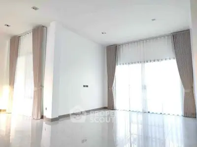 Spacious and bright living room with large windows and elegant curtains, perfect for modern living.