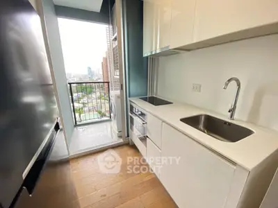 Modern kitchen with sleek white cabinets and balcony view in urban apartment