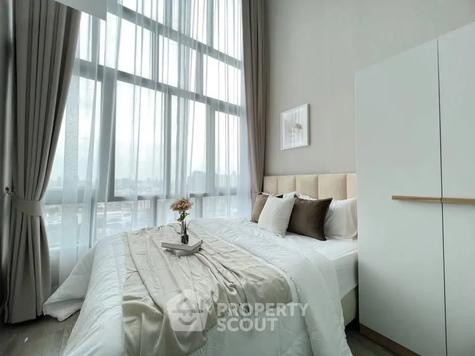 Luxurious bedroom with floor-to-ceiling windows and elegant decor in modern apartment.