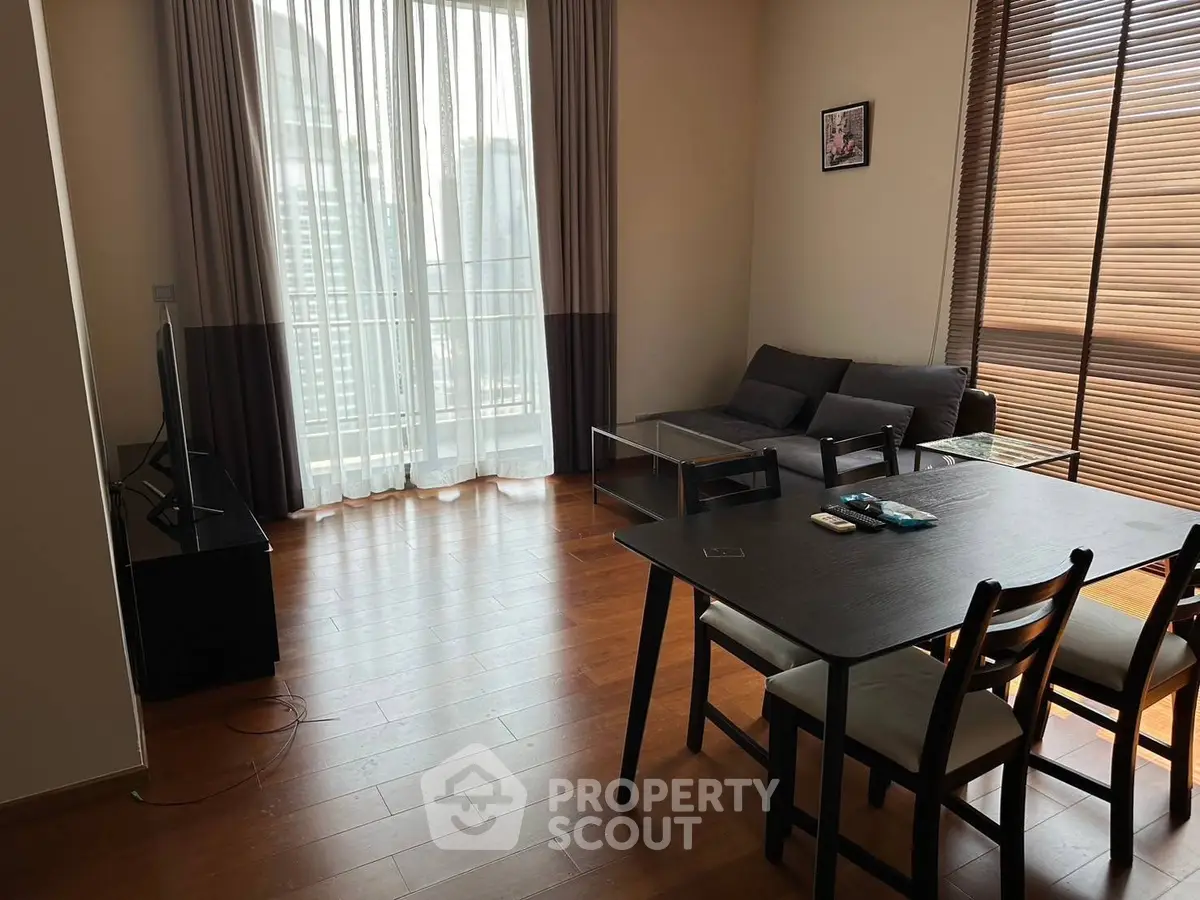 Modern living room with large windows and wooden flooring, featuring a cozy sofa and dining area.