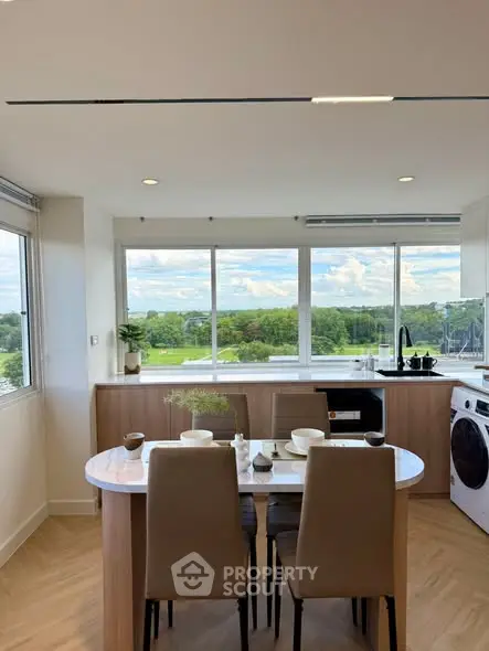 Modern kitchen with open layout and scenic view, featuring sleek appliances and elegant dining area.