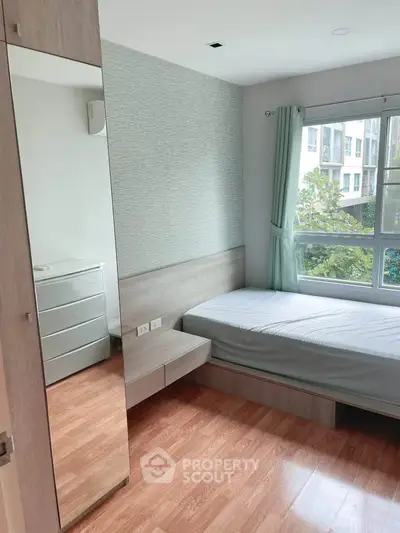 Modern bedroom with large window and wooden flooring in a stylish apartment.